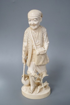 A Japanese carved ivory figure of a farmer, Meiji period, c.1900, signed, carrying a lantern on a stick, maize grows at his feet, a toad climbs on one arm, height 20.5cm